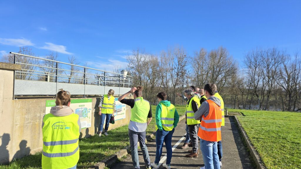 Groupe en visite pédagogique à la station d'épuration, encadré par un animateur en gilet orange