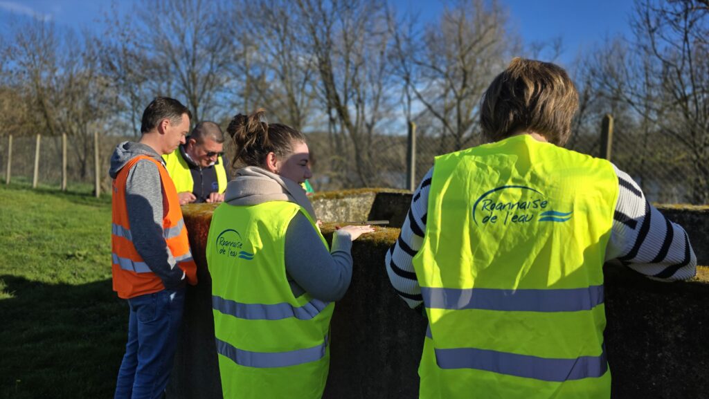 Petit groupe de visiteurs et animateur Roannaise de l'Eau autour d'un équipement extérieur de la station